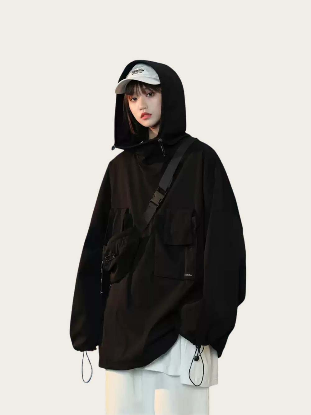 Person wearing a black hoodie and white pants on a plain background