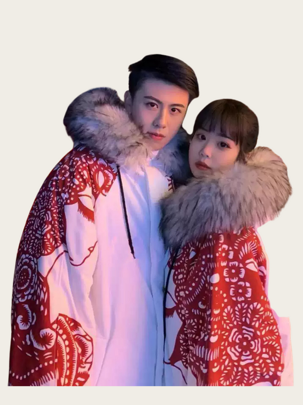 Two people wearing red and white patterned coats with fur hoods against a light background