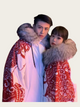 Two people wearing red and white patterned coats with fur hoods against a light background