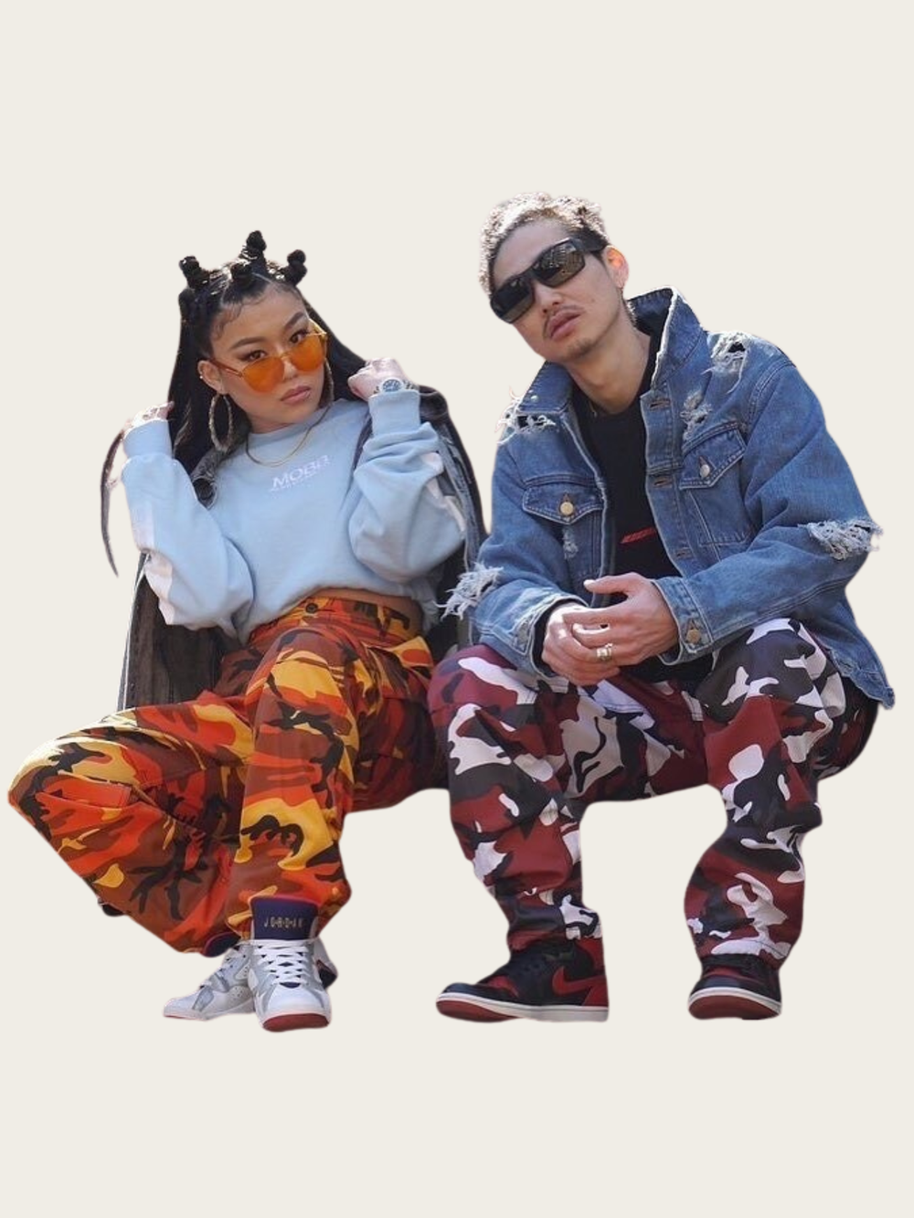 Two people posing together wearing colorful outfits with a plain background