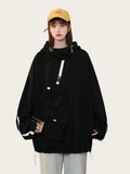 Person wearing a black hoodie with multiple pockets on a plain background