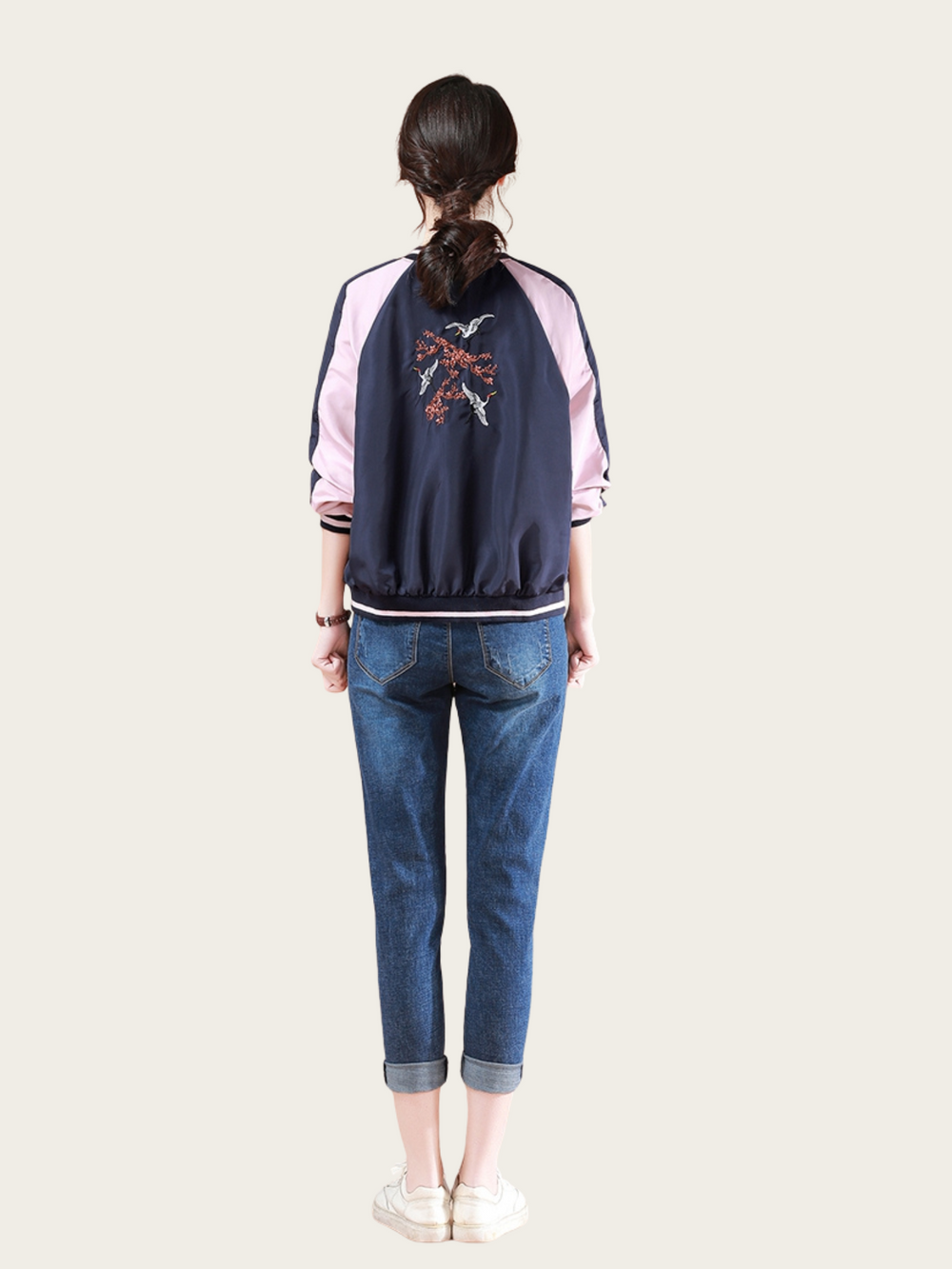 Person wearing a navy and pink jacket with a design on the back, standing against a white background.