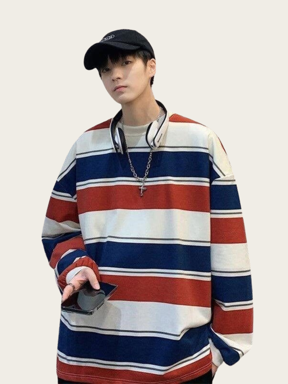 Person wearing a colorful striped sweater and black cap on a plain background