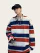 Person wearing a colorful striped sweater and black cap on a plain background