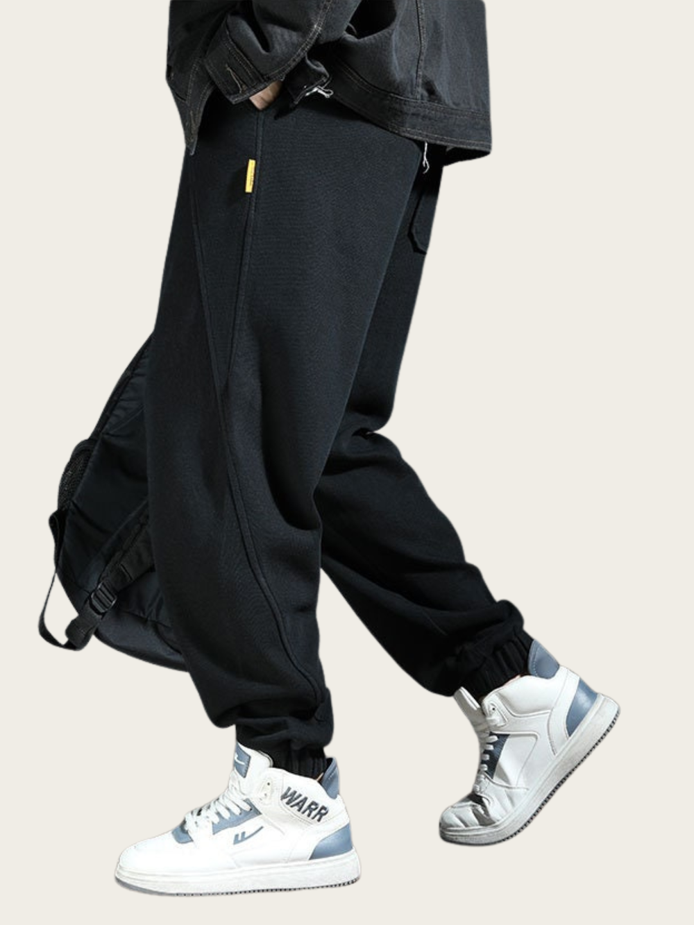 Person wearing black cargo pants and white sneakers on a beige background