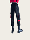 Black cargo pants with red accents worn by a person on a beige background