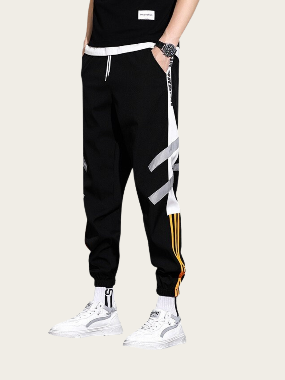 Person wearing black jogger pants with white and gold stripes on a white background