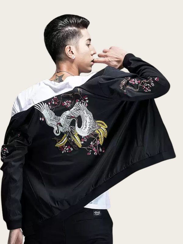 Person wearing a black jacket with floral embroidery on a plain background