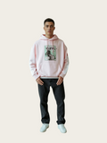 Person wearing a light pink hoodie with a graphic design on a plain background