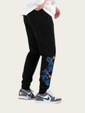 Black jogger pants with colorful embroidery on a white background