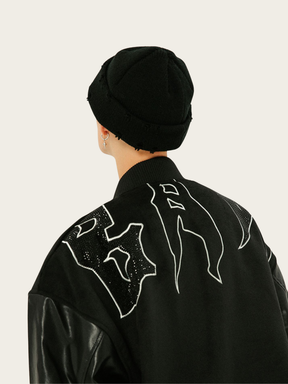 Person wearing a black outfit with white designs on a light gray background