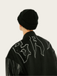 Person wearing a black outfit with white designs on a light gray background