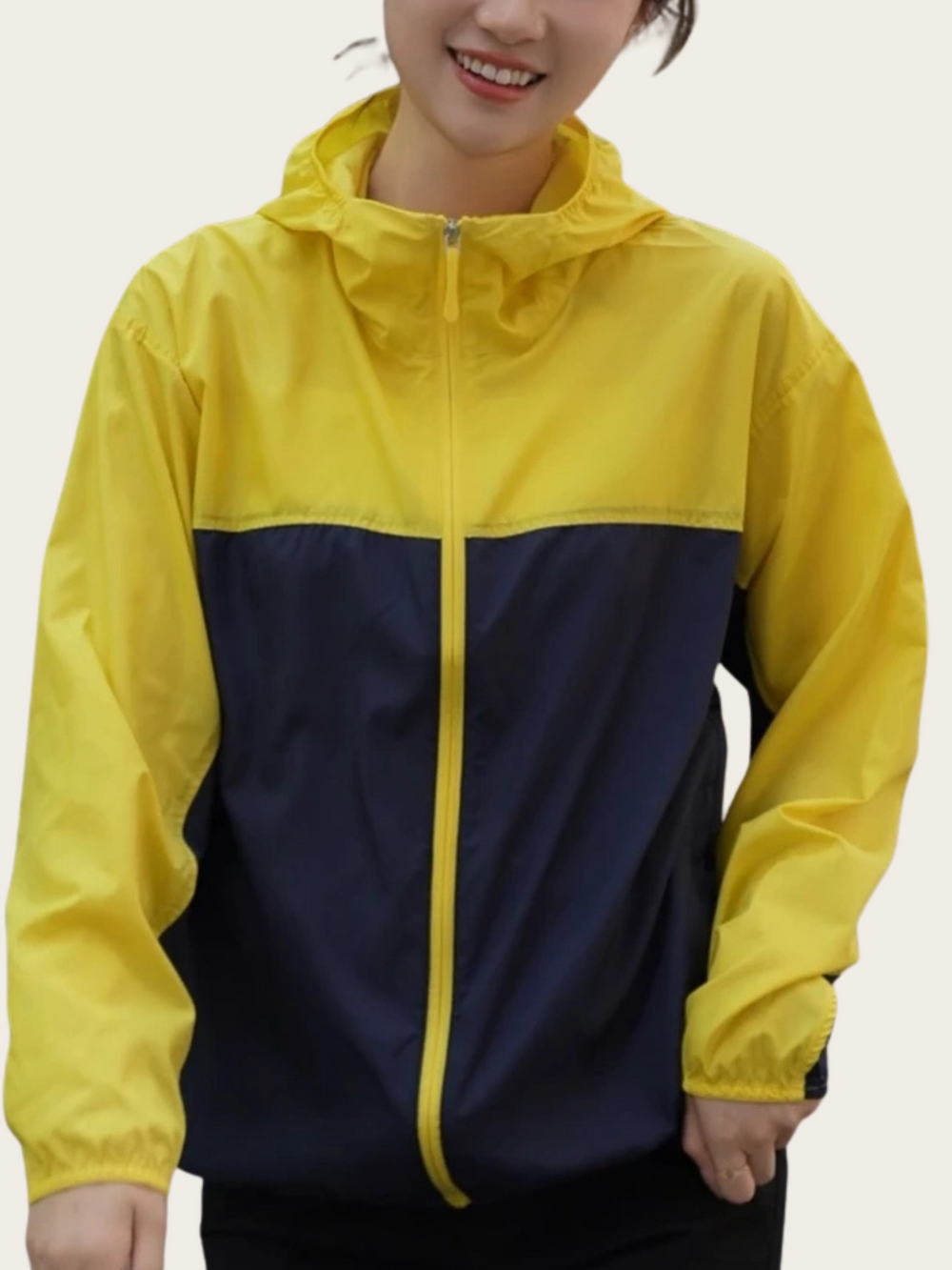 Person wearing a yellow and navy raincoat on a plain background