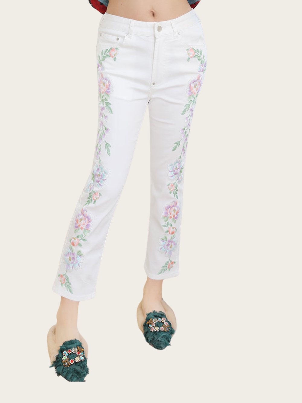 White jeans with floral embroidery worn by a person on a white background