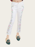 White jeans with floral embroidery worn by a person on a white background
