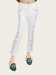 White jeans with floral embroidery worn by a person on a white background