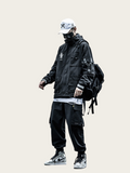Person wearing a black jacket, pants, and sneakers with a backpack on a beige background