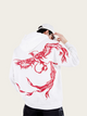 Person wearing a white hoodie with red dragon design on the back against a beige background