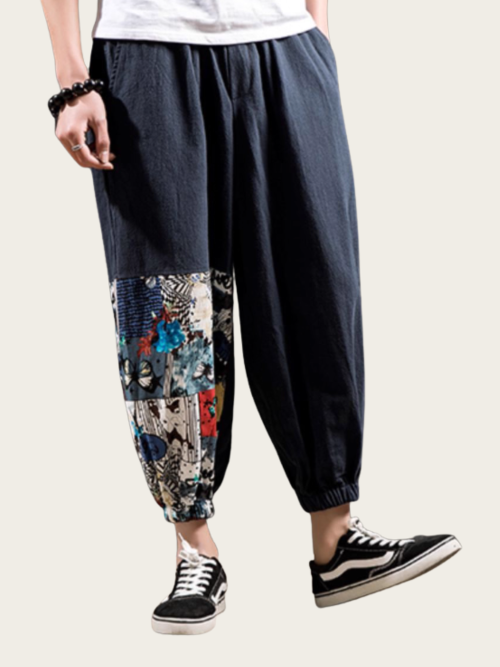 Dark blue pants with floral patchwork design worn by a person on a white background