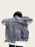 Person wearing a gray denim jacket with patches on a white background