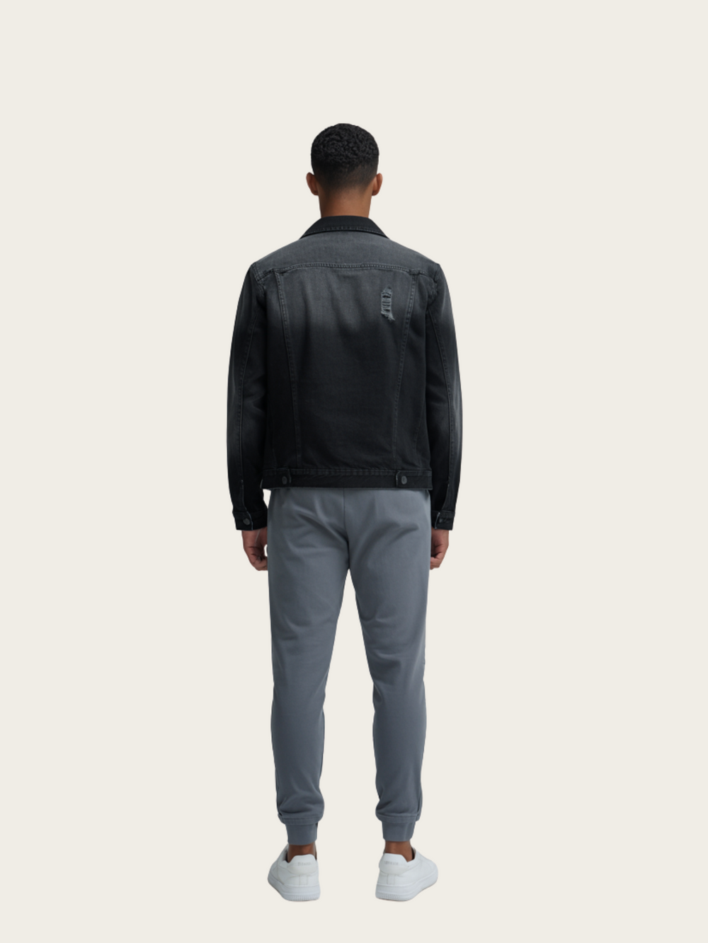 Man wearing a black jacket and gray pants on a beige background