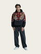 Person wearing a colorful hoodie with a dragon design on a plain background