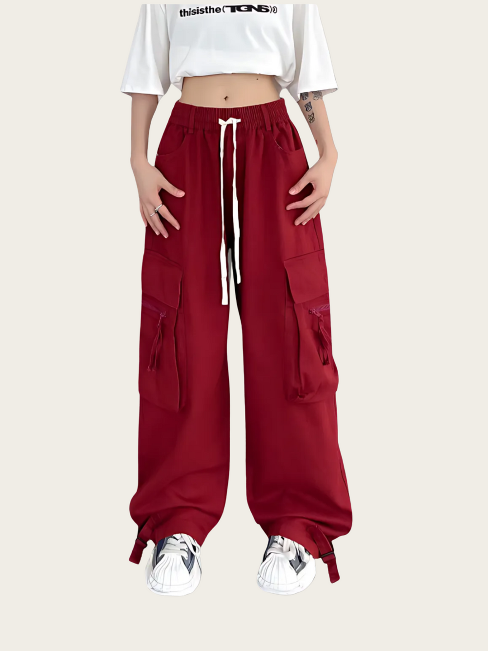 Person wearing red cargo pants with a white crop top on a light gray background