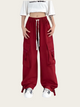 Person wearing red cargo pants with a white crop top on a light gray background