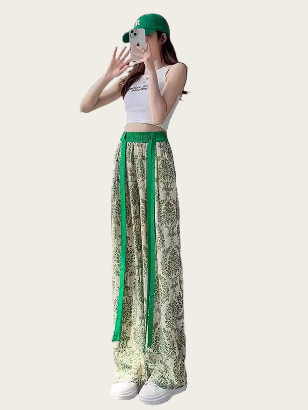 Person wearing a white top and green and beige patterned pants on a white background