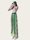 Person wearing a white top and green and beige patterned pants on a white background