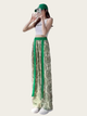Person wearing a white top and green and beige patterned pants on a white background