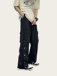 Person wearing black cargo pants with white buttons on a plain background