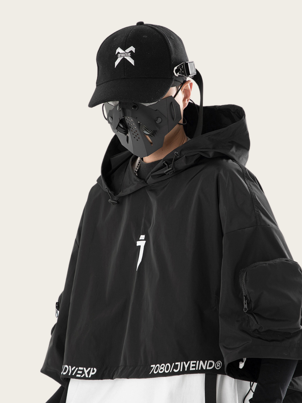 Person wearing a black cap and jacket with brand logos on a light gray background