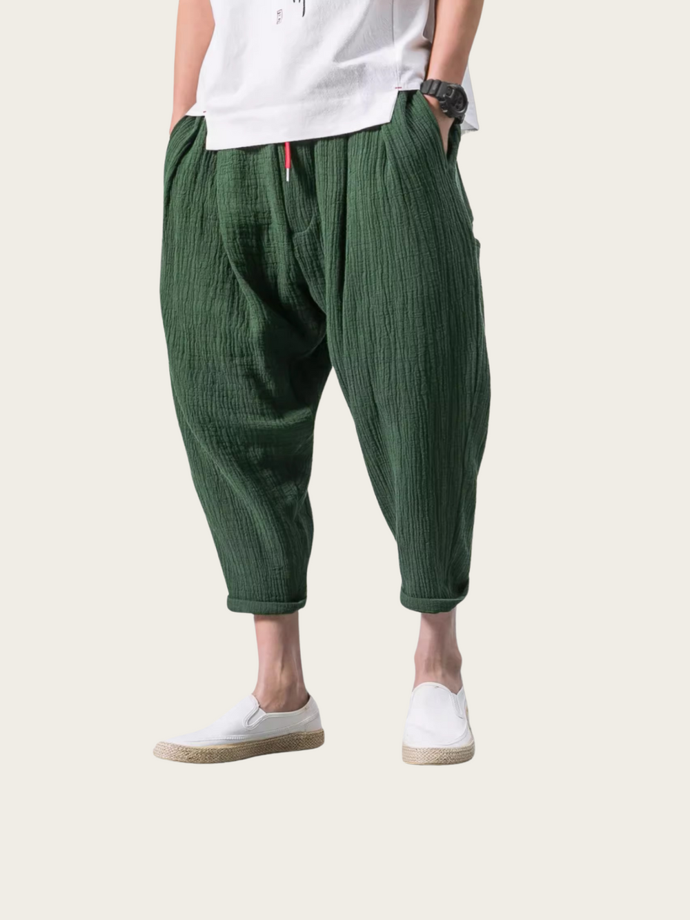 Person wearing green harem pants and white shoes on a light gray background