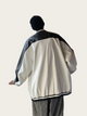 Person wearing a black and white jacket with a plain background