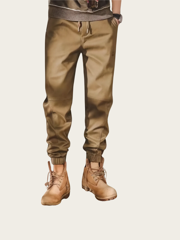 Person wearing brown jogger pants and boots on a beige background