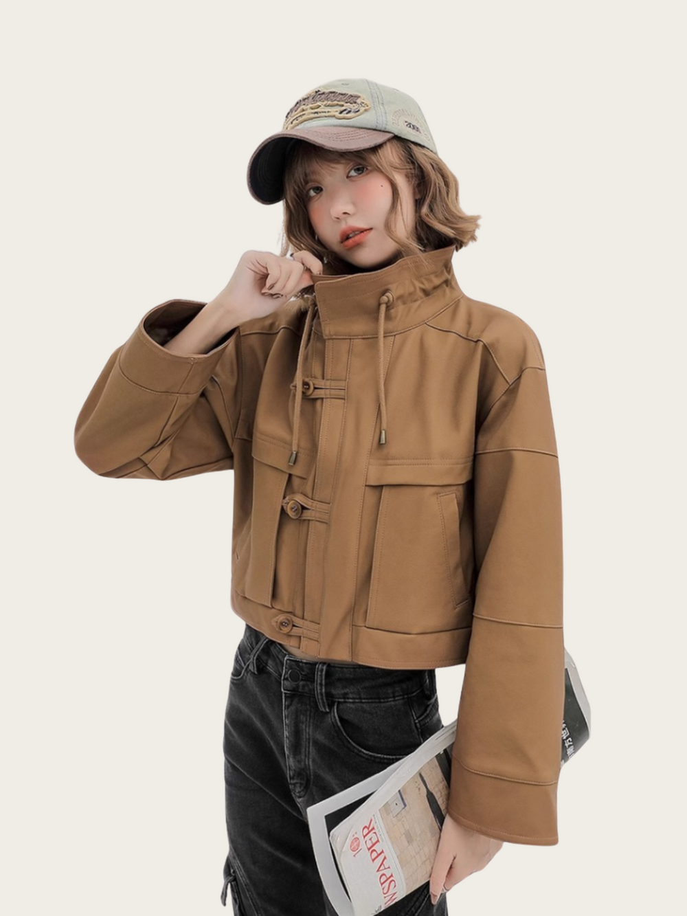 Person wearing a brown jacket and black pants with a beige cap on a white background