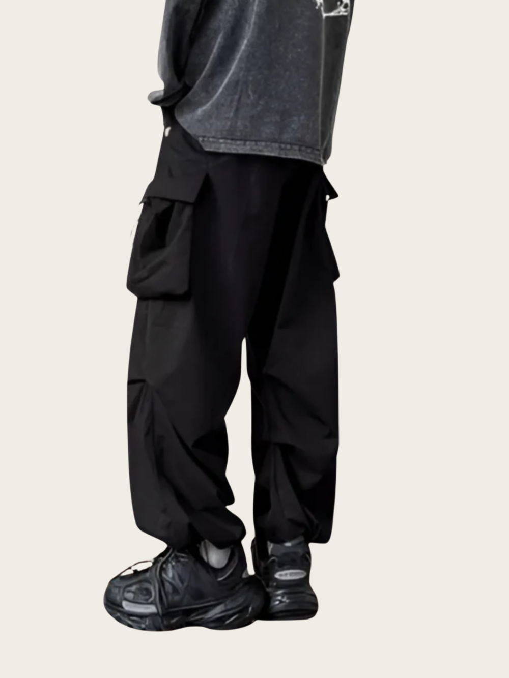 Person wearing black cargo pants and black sneakers on a light gray background