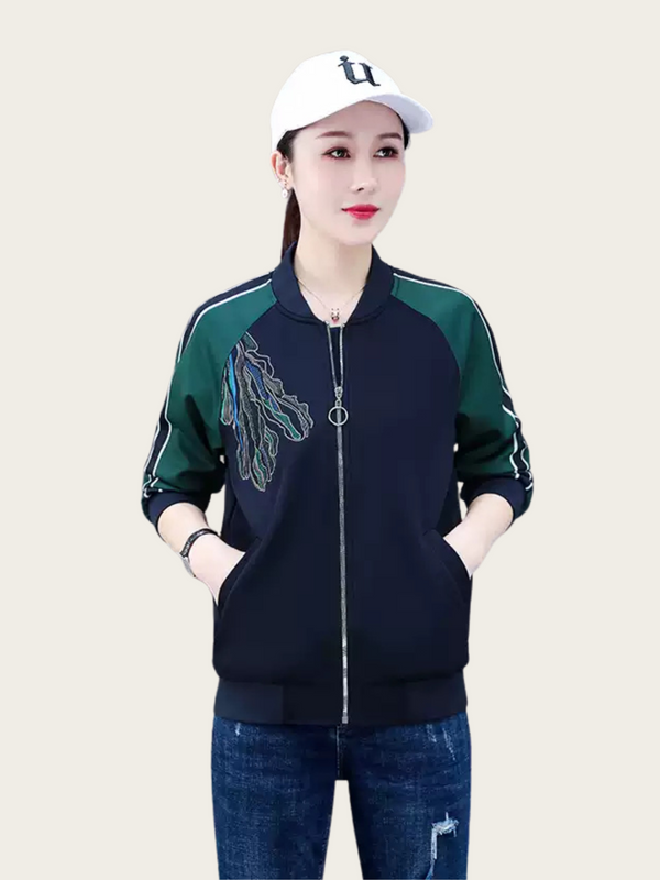 Woman wearing a dark blue jacket with green accents and a white cap on a beige background