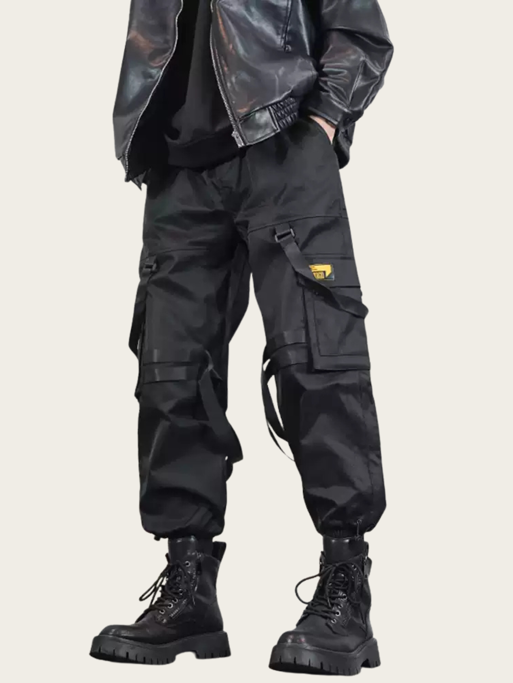 Person wearing black cargo pants and boots on a light gray background