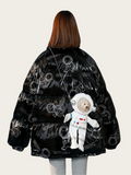 Black jacket with astronaut design and teddy bear plush toy on a plain background