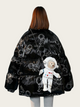 Black jacket with astronaut design and teddy bear plush toy on a plain background