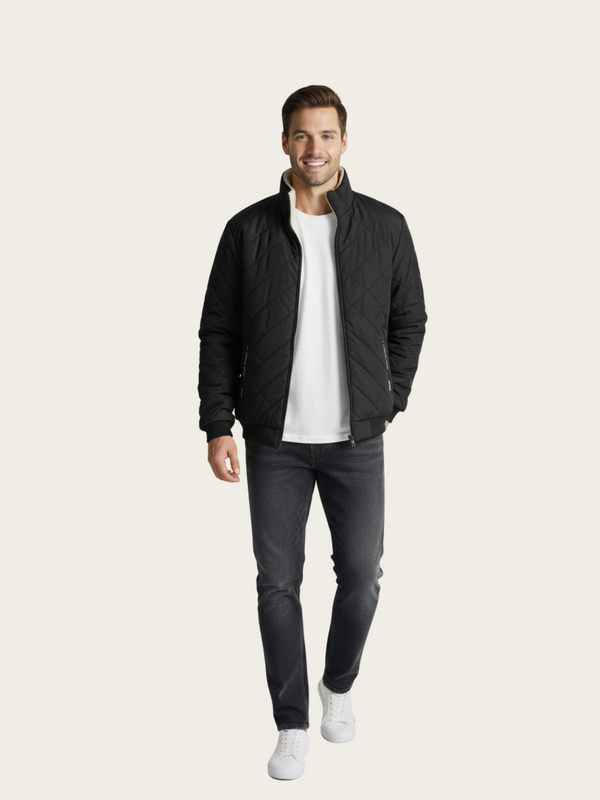 Man wearing a black jacket, white shirt, and dark jeans on a light background