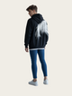 Person wearing a black hoodie with a white horse tail design on a plain background