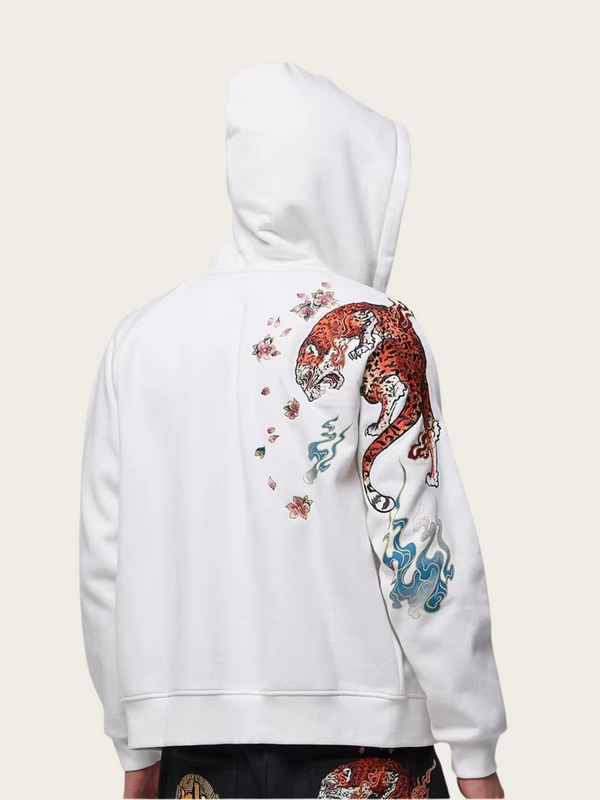 White hoodie with colorful tiger design on the back against a beige background