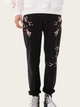 Black pants with floral embroidery worn by a person on a white background