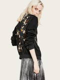 Woman wearing a black bomber jacket with floral embroidery on a white background