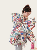 Person holding a colorful cartoon-patterned baby carrier with a plain background