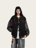 Person wearing a black varsity jacket with colorful designs on a white background