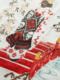 Embroidered design of a red bridge with floral patterns on a white background